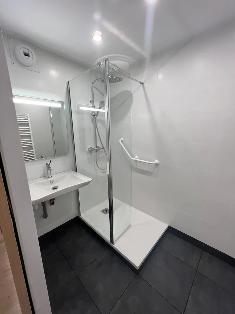 Espace de douche accessible avec sol antiderapant et commande d'eau deportee
